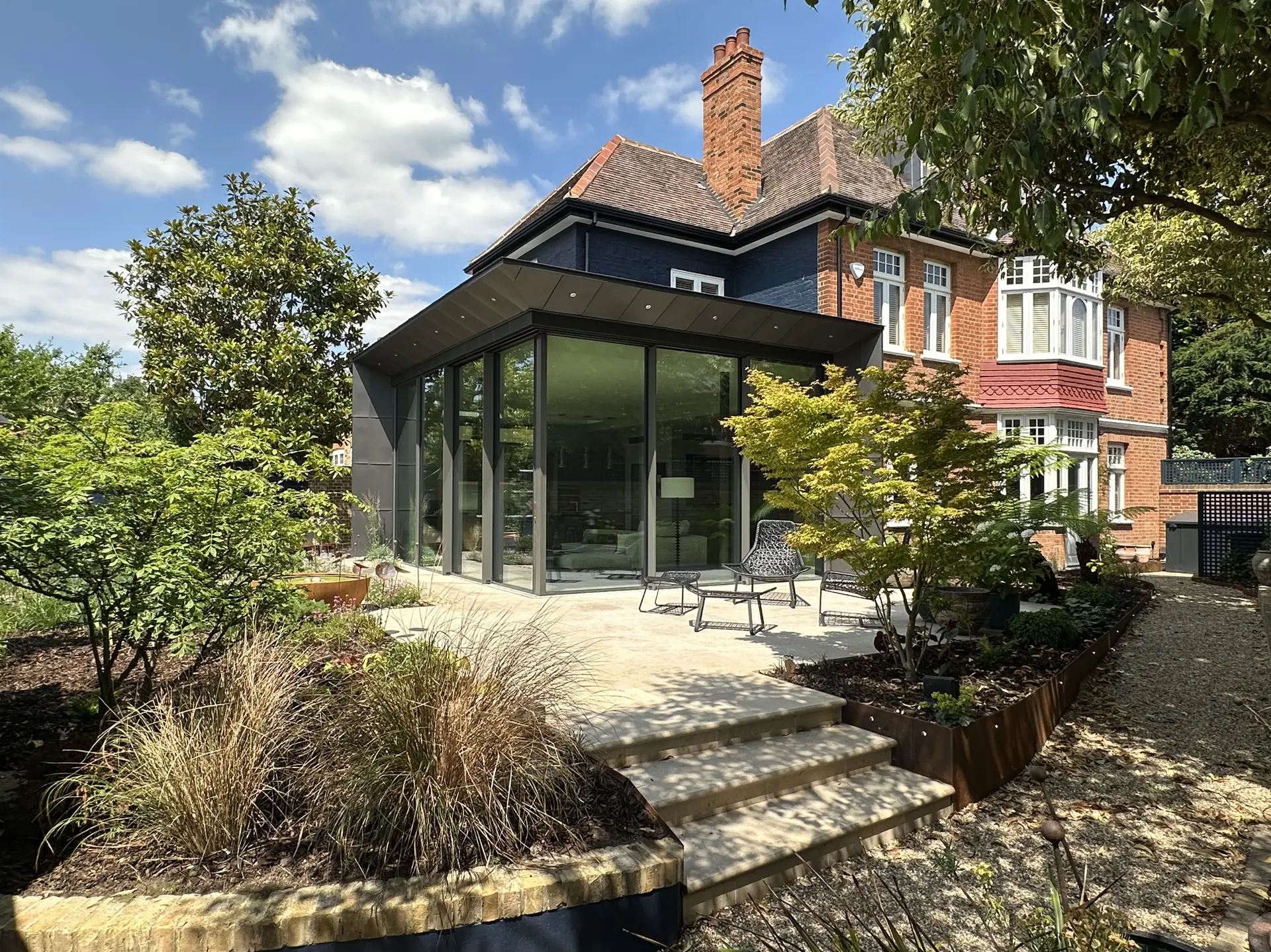 Contemporary brick infill home with modern detailing, large windows, and an integrated entrance, blending with historic terraced houses.