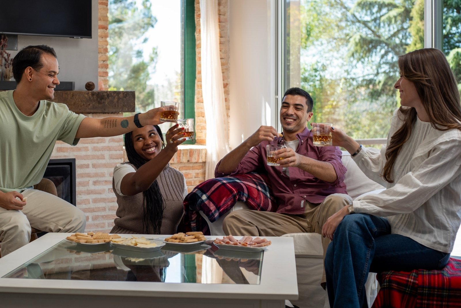 Groupe de 5 à 7 amis adultes autour d'une table, verres levés, sourires larges, ambiance de fin de soirée chaleureuse. Restes d'apéro sur la table — fromages, charcuterie, bouteilles. Lumière tamisée, atmosphère de complicité et de réussite collective.