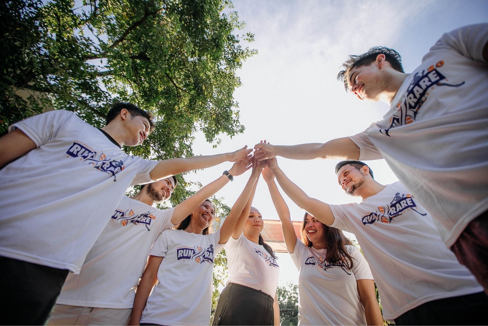 Groupe souriant après une session d'escape game en extérieur, ambiance décontractée et conviviale, contexte estival avec lumière dorée, personnes debout en cercle, regard caméra avec expression de satisfaction et de connivence.