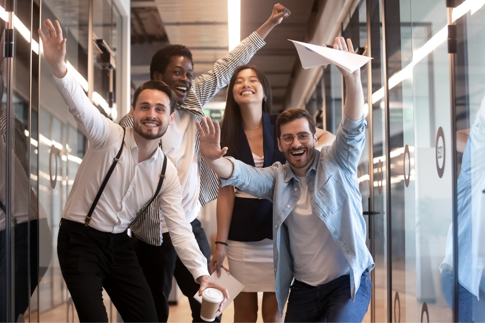 Équipe de collaborateurs souriants levant les mains en signe de victoire après avoir résolu l'énigme finale, décor extérieur estival ou bureau lumineux, ambiance conviviale et de réussite collective.