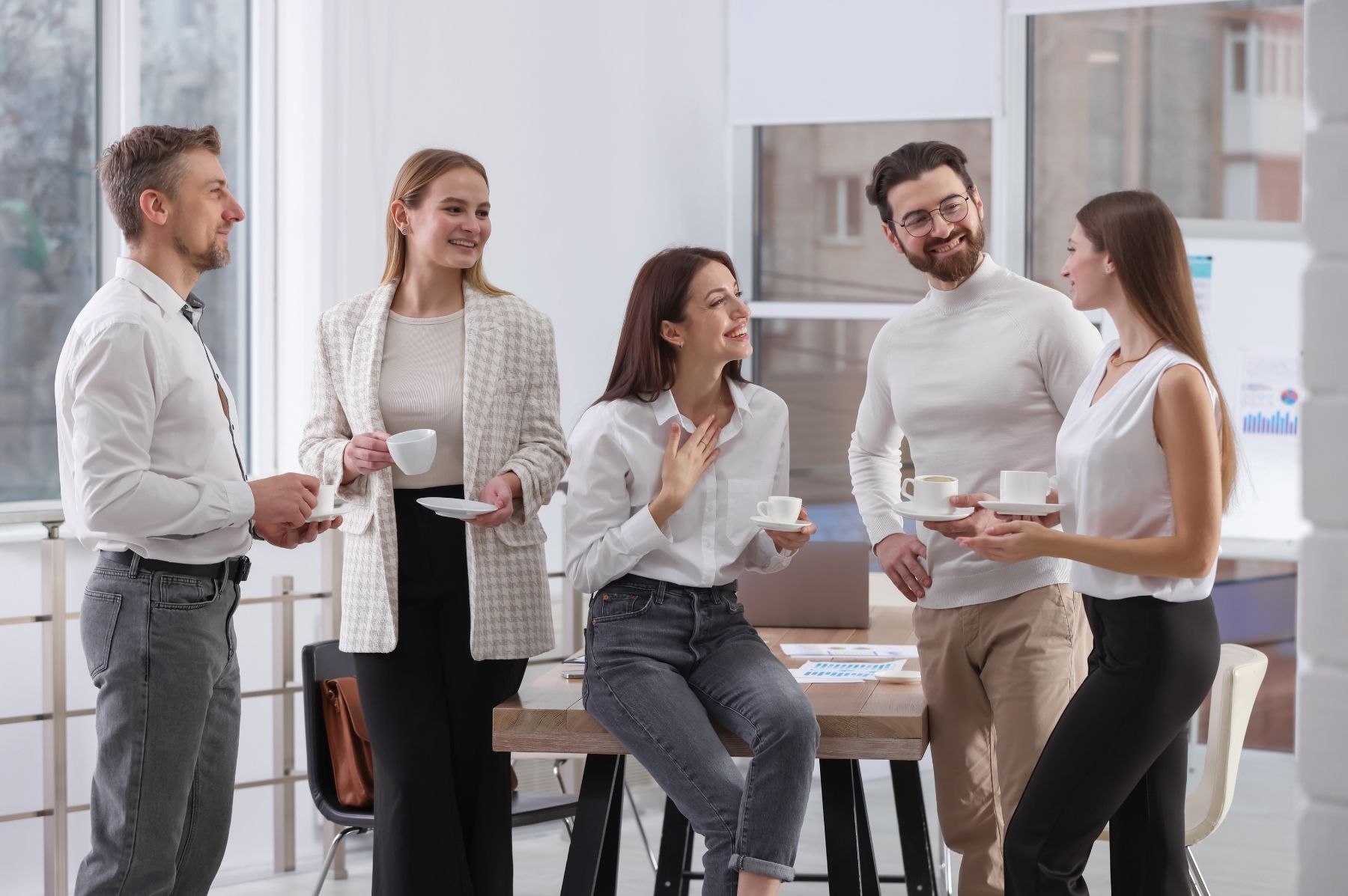 Un bureau en open space à moitié vide un après-midi d'août, quelques collaborateurs regroupés autour d'une seule table plutôt que dispersés à leurs postes, lumière d'été traversant les fenêtres, ambiance détendue et légèrement suspendue.