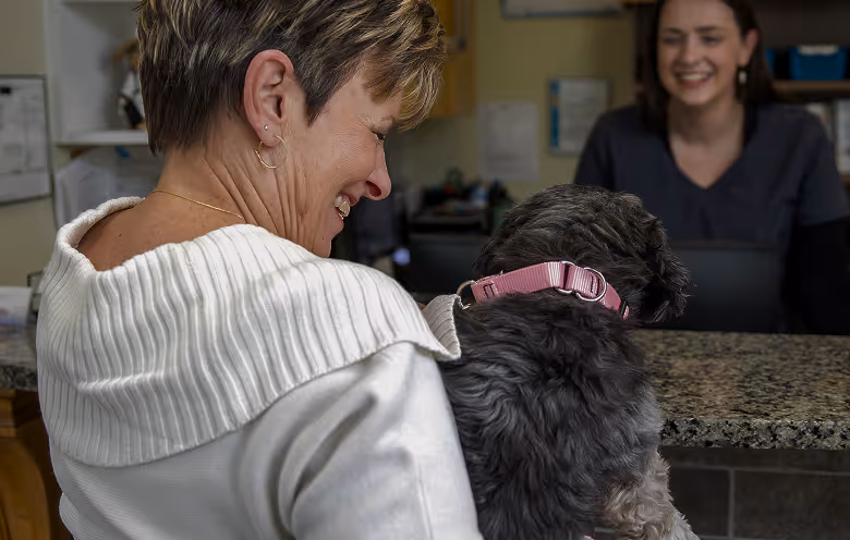 a woman smiling at a dog