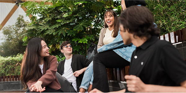 Group of UCL students sitting outside and laughing. 
