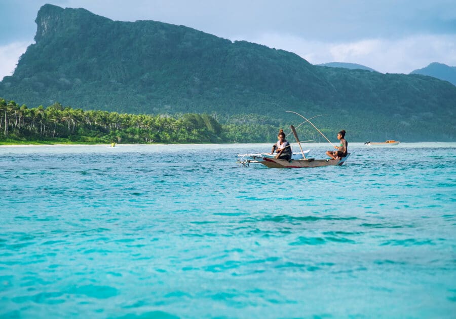 Rah Island, Vanuatu. Two young islander women sit on wooden boat fishing.
