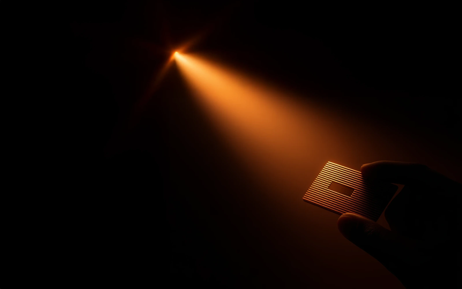 Hand holding an RFID tag lit by a beam of light representing radio waves.