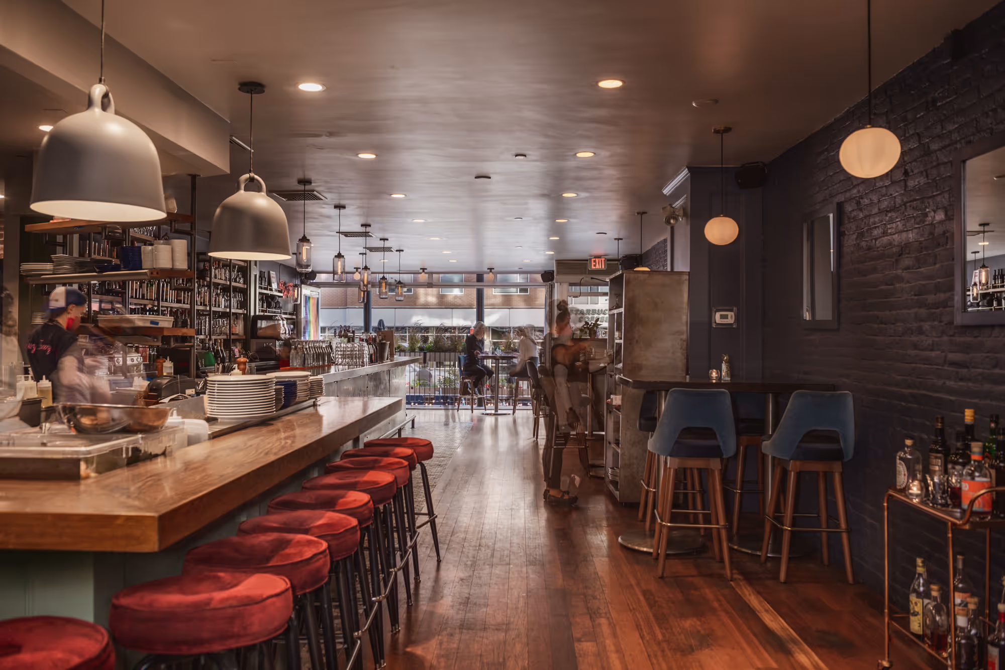 Retail space owned by Torrington that shows a warm, inviting restaurant interior with a long wooden bar lined with red cushioned stools.