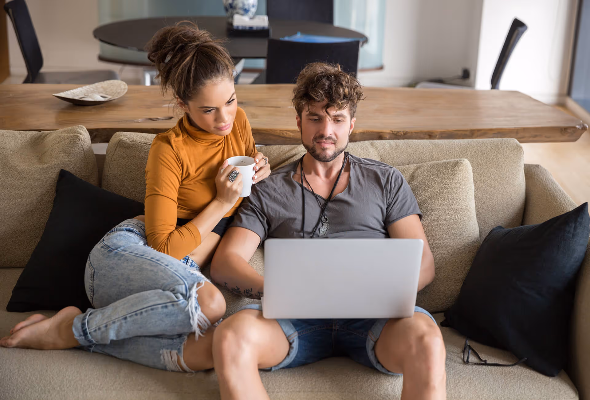 A couple looking at the computer while sitting on a couch.