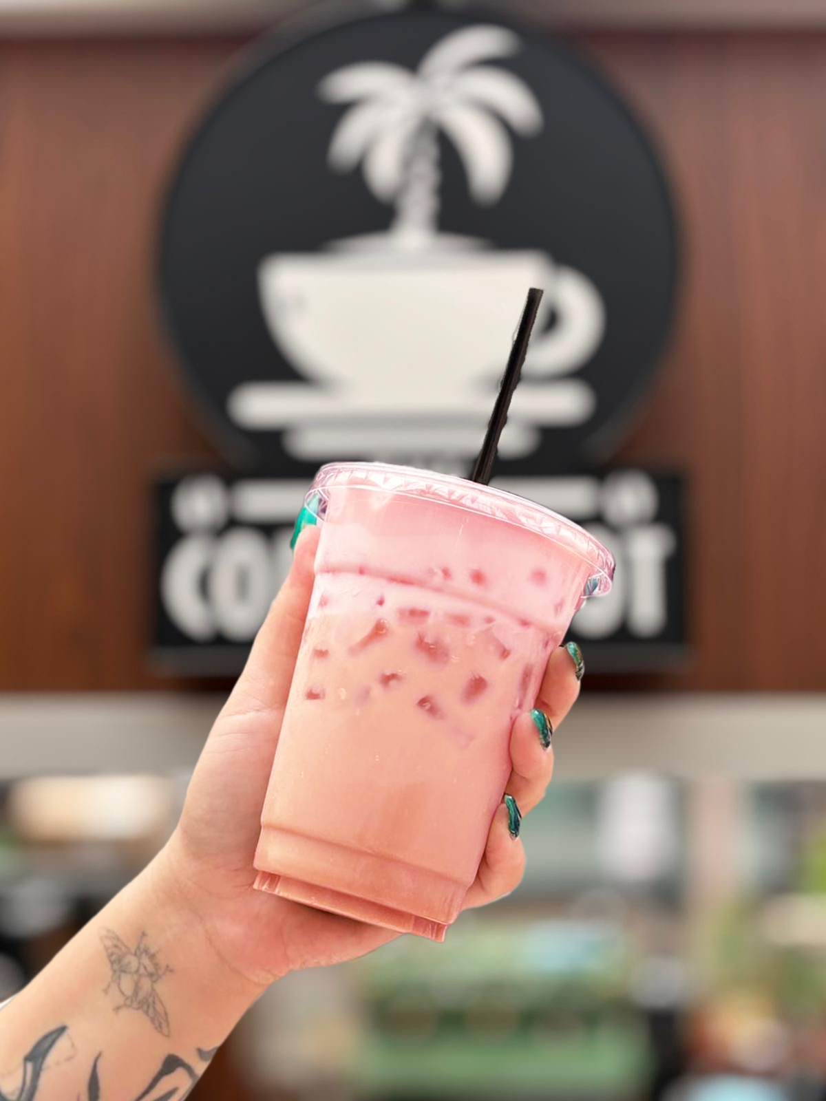 person holding up specialty drink, chai tea and cherry cold foam.