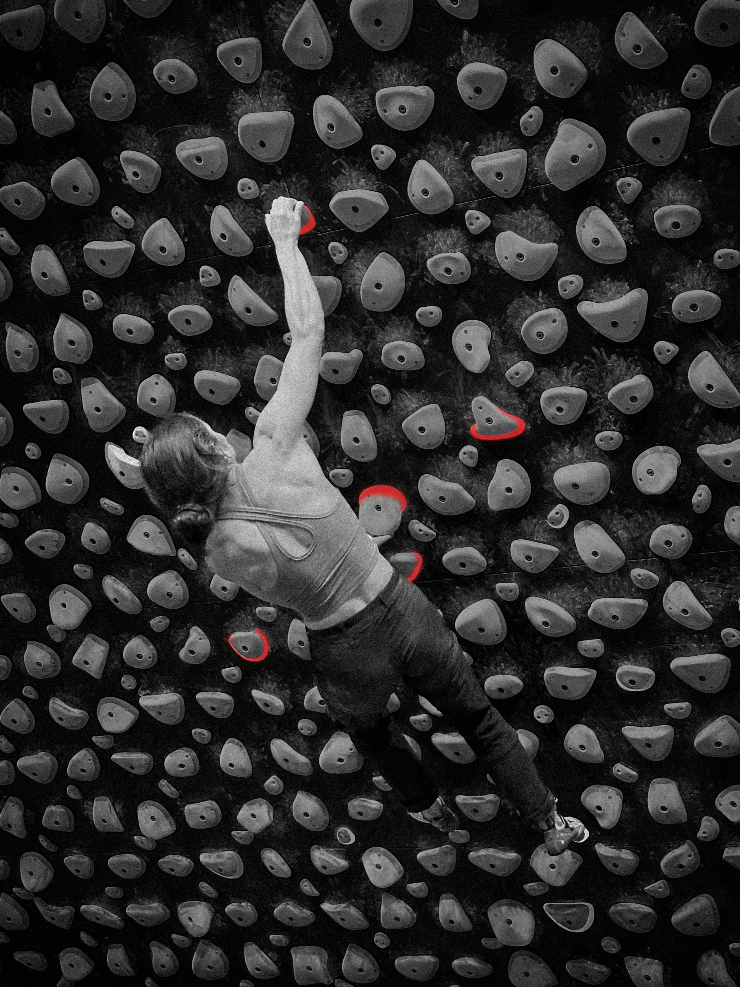 Black and white photo of a woman climbing on a Kilter climbing board.