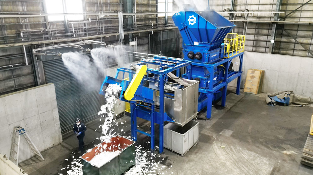 An industrial shredder processing mill waste inside a warehouse.