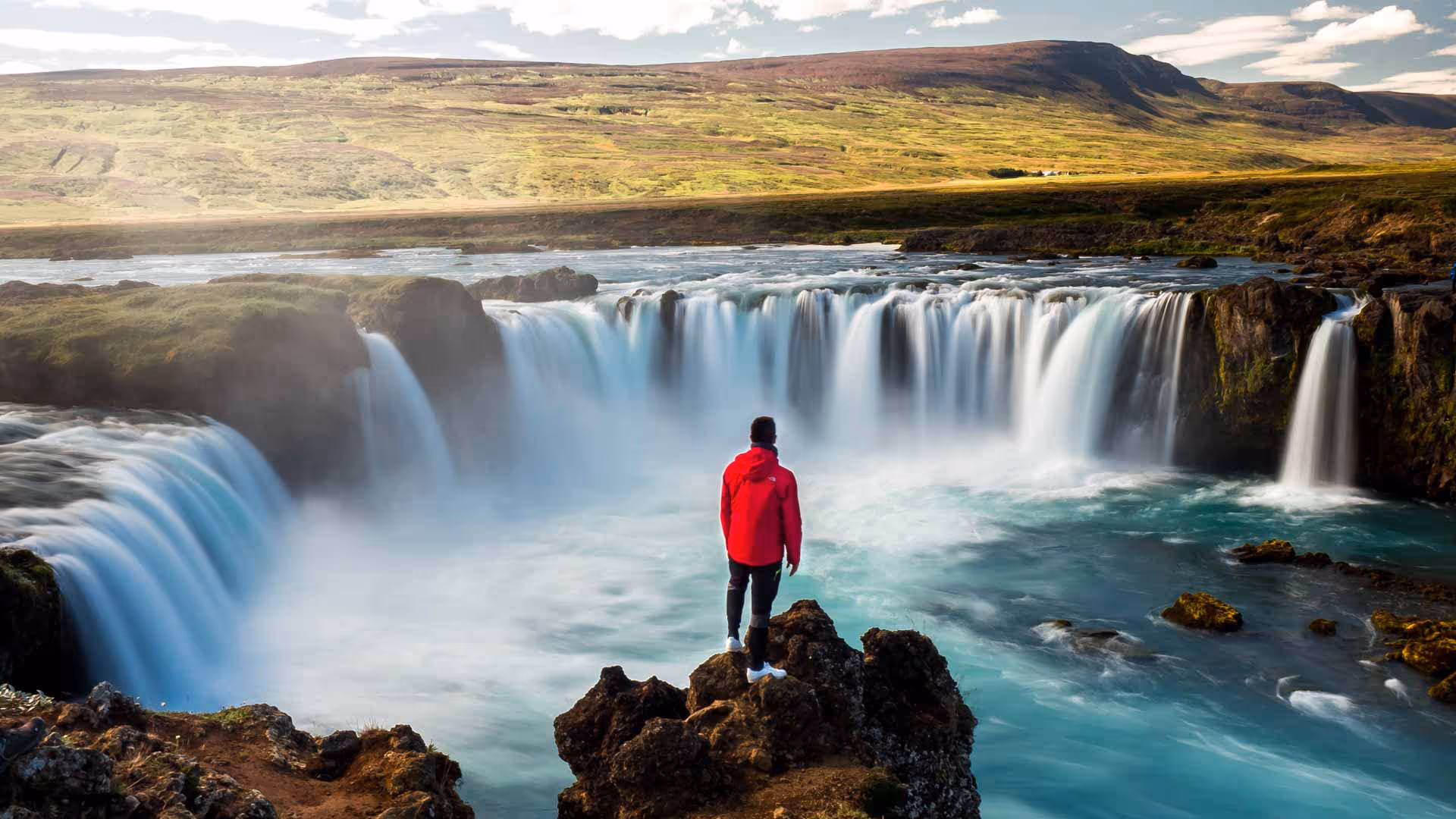 Man standing in front of a large waterfall