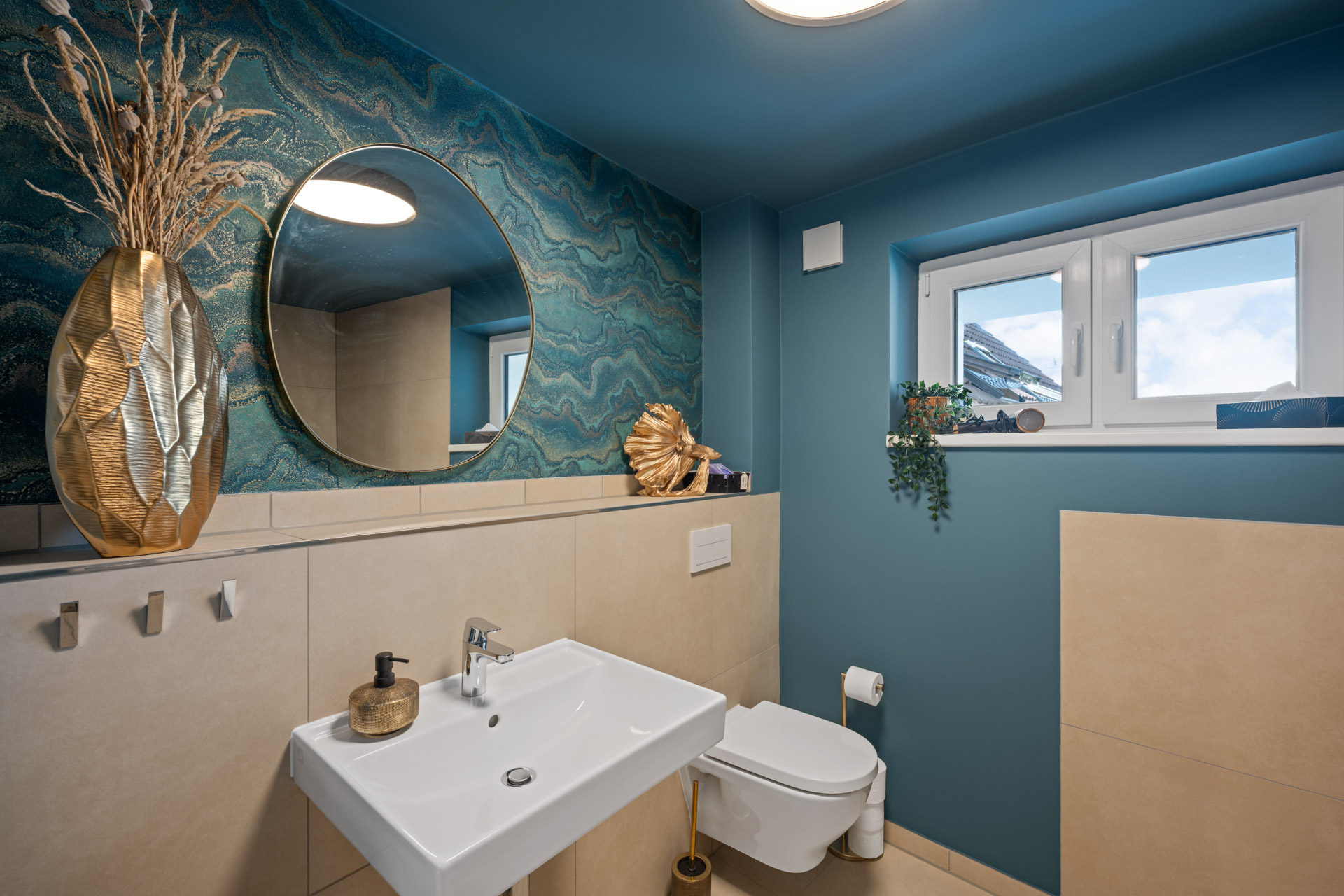 Badezimmer der Ferienwohnung Eisvogel mit Waschbecken, WC und rundem Spiegel