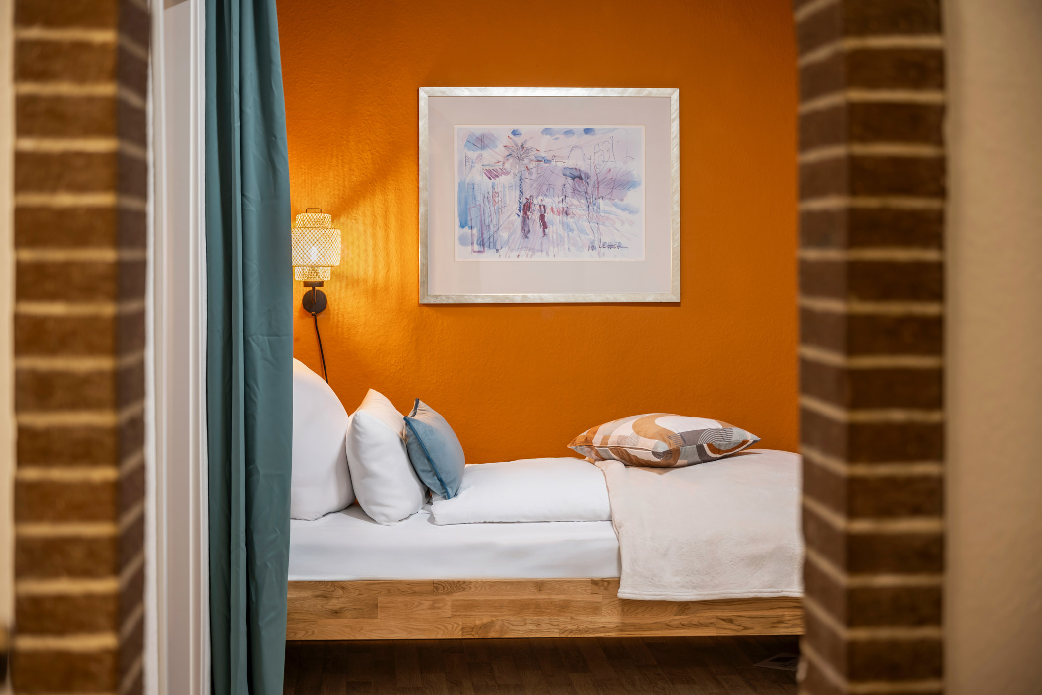 Einzelbett der Ferienwohnung Sperling hinter dem Backsteinbogen