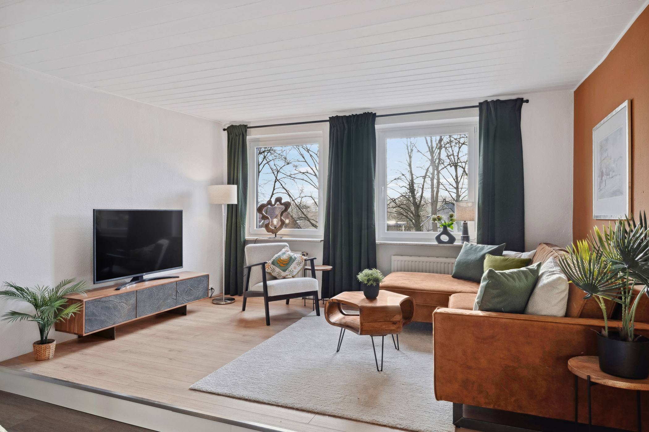 Wohnzimmer der Ferienwohnung Sperling mit Sofa, Smart-TV und Blick ins Grüne