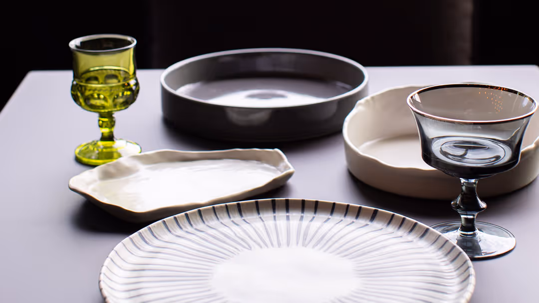 A place setting for two featuring a variety of unique, ceramic plates and dishes and colorful, unique goblets