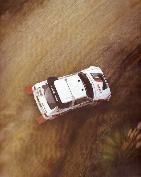 Vue aérienne d’une Peugeot 205 T16 EVO2 du Groupe B filant à pleine vitesse sur une piste de terre en 1985.
