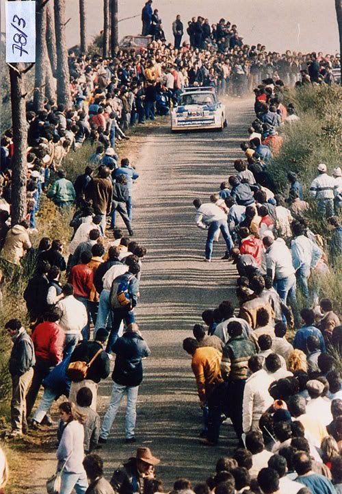 Une foule compacte bordant une route en gravier observe le passage d’une voiture du Groupe B pendant le Rallye du Portugal 1983.