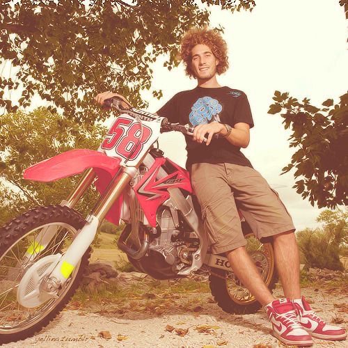 Marco Simoncelli posant décontracté sur une motocross Honda CRF rouge.