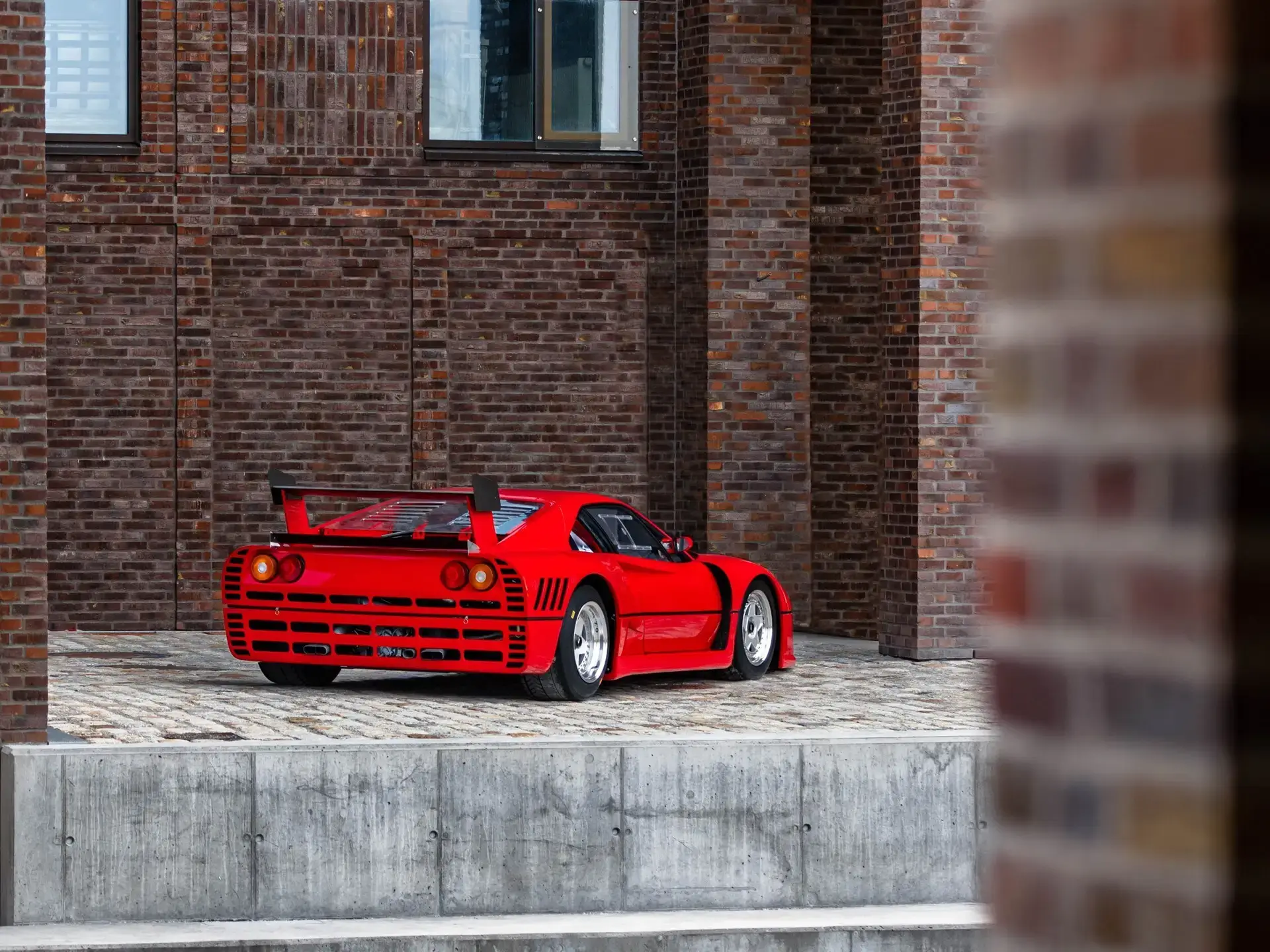 Ferrari 288 GTO Evoluzione garée devant un bâtiment moderne, symbole du design Pininfarina.