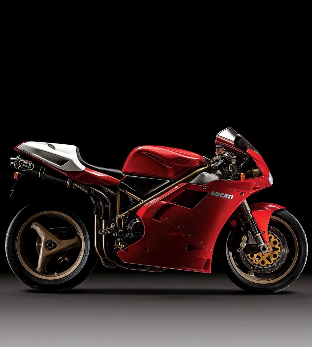Vue latérale de la Ducati 916, cadre treillis doré et carénage rouge brillant sur fond neutre