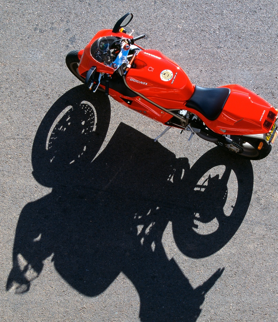 Vue aérienne d’une Ducati 916 projetant son ombre sur le bitume, photographie signée Phil Aynsley