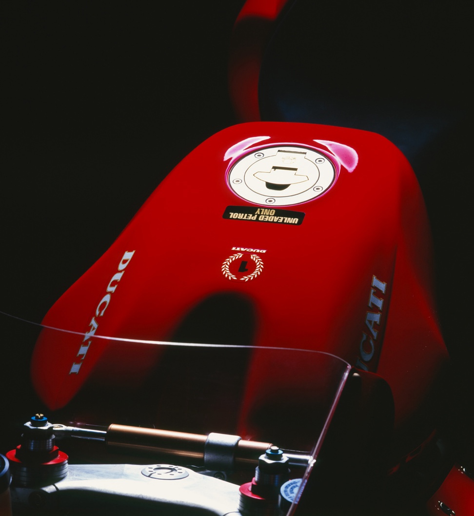 Gros plan sur le réservoir et la trappe à essence d’une Ducati 916, symbole de pureté et de finition italienne