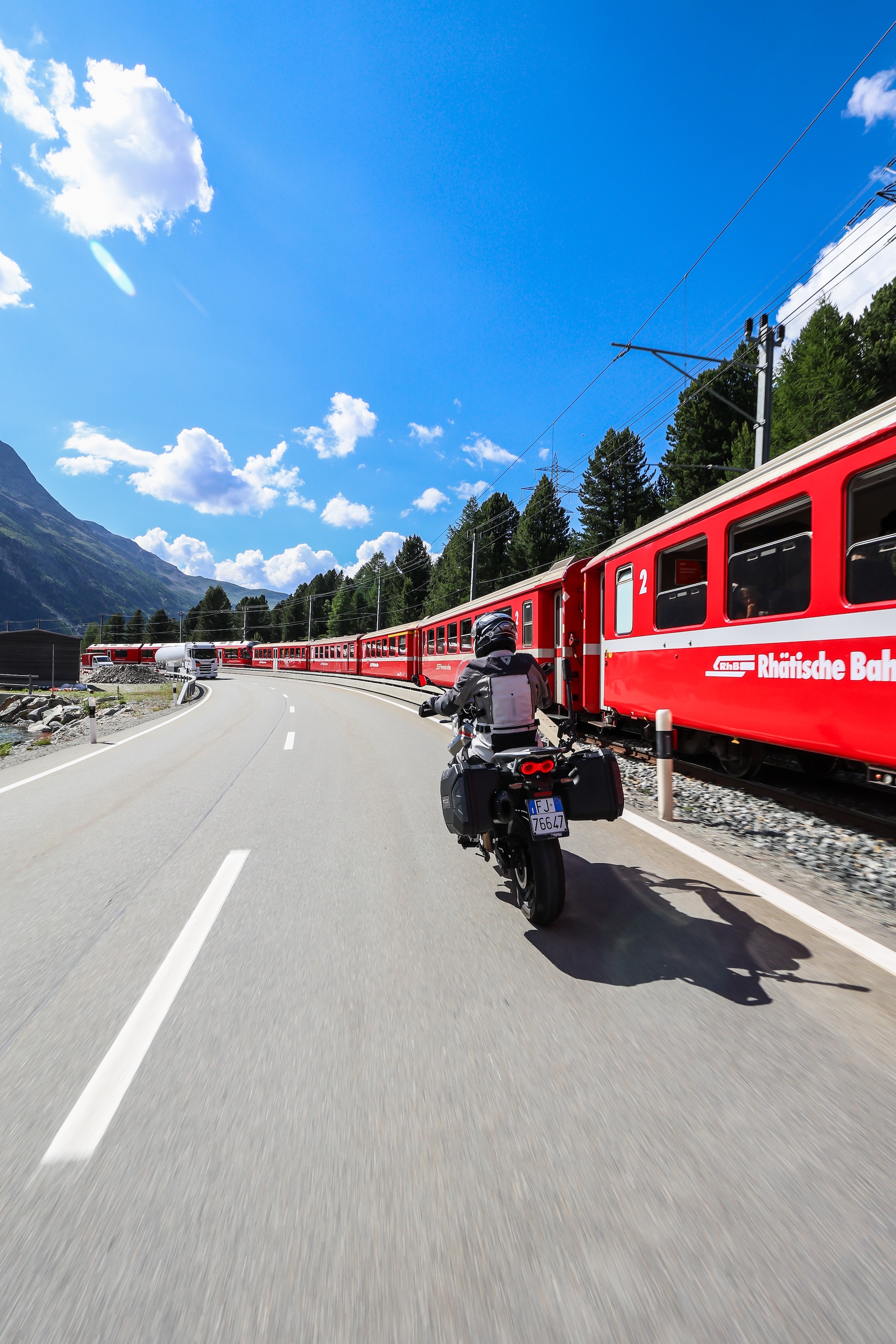 Moto Guzzi V85 TT arrêtée près de la voie du Bernina Express dans les Alpes suisses