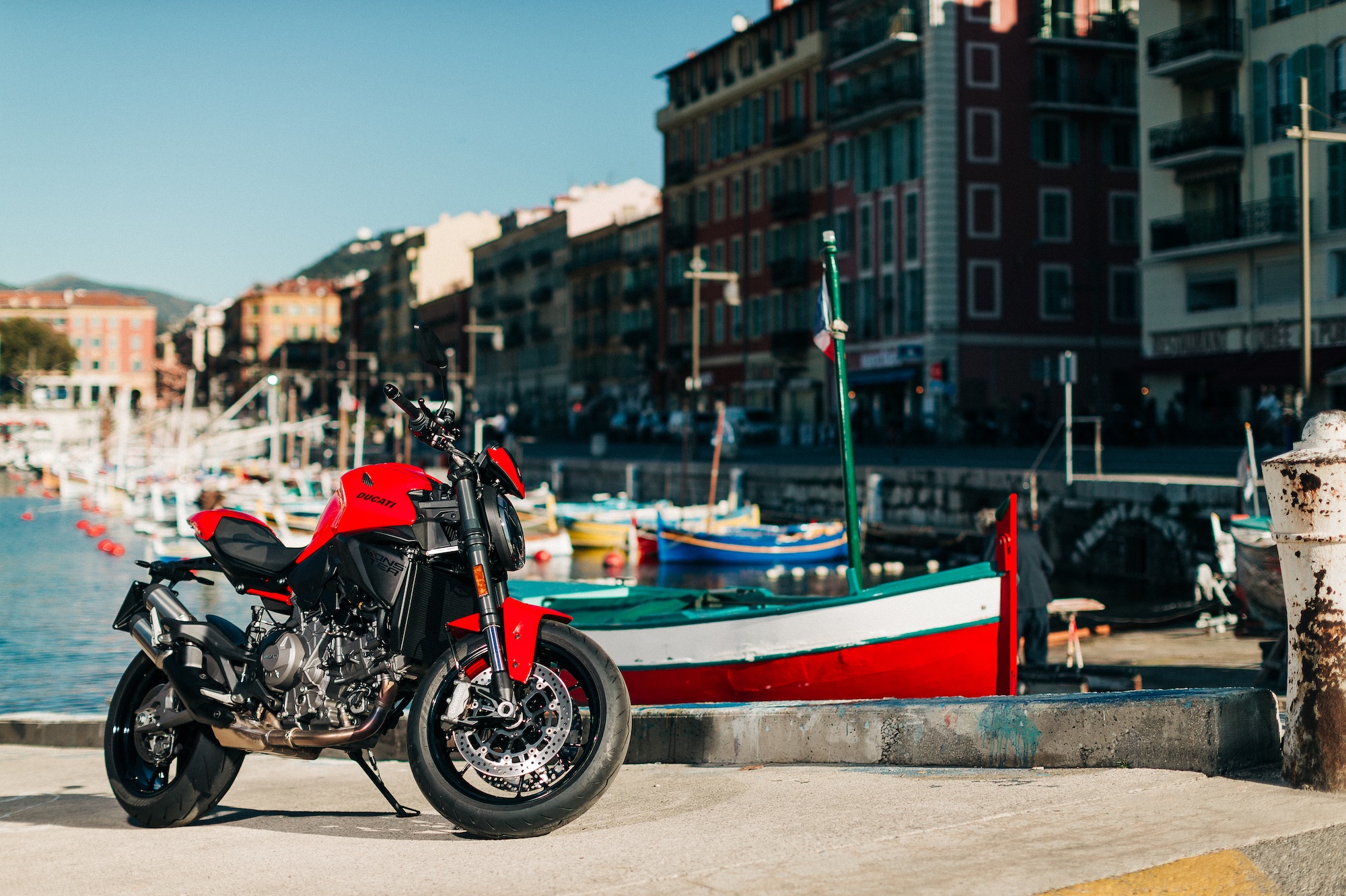 Le Ducati Monster 2026 pose de profil sur le port de Nice avec des vieux bateaux derrière
