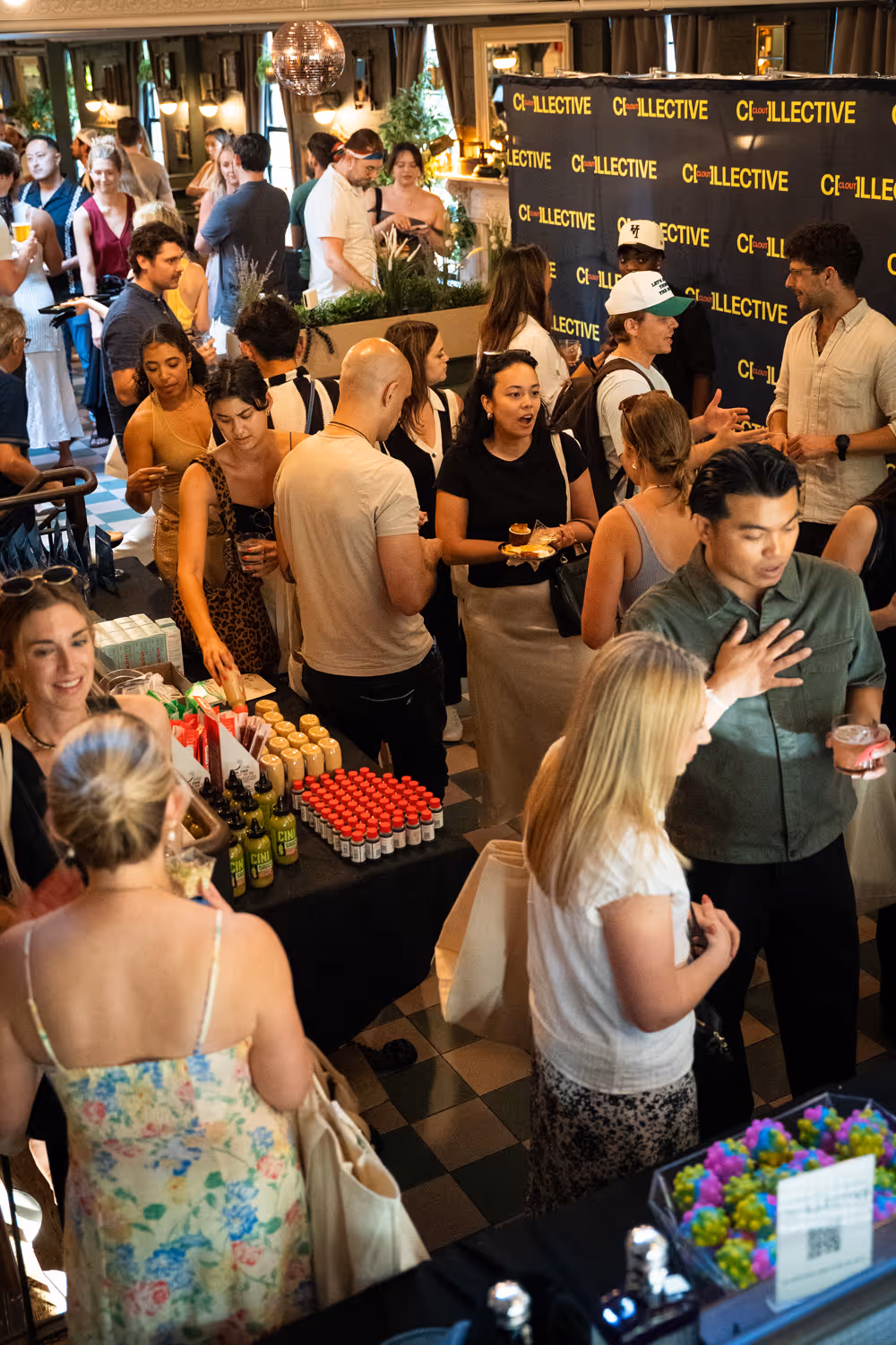 Crowd of people socializing and sampling products at an indoor event with Clout Collective branding.