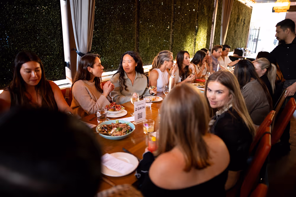 Group of people sitting around a long table enjoying a meal and conversation in a restaurant.