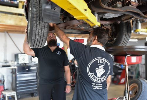 Price Automotive crew works on the underside of a car that's been lifted.