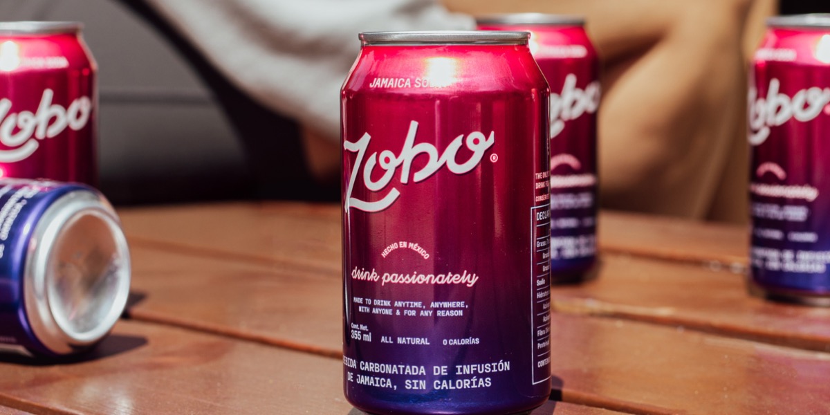Several red and purple cans of Zobo Jamaica soda on a wooden surface.
