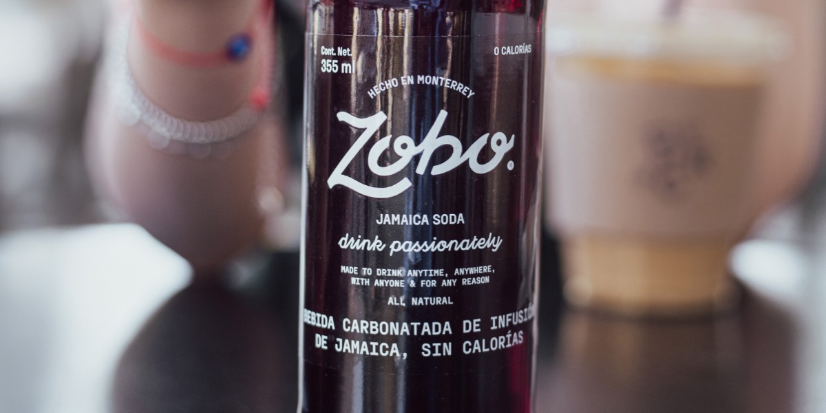 Close-up of a 'Zobo Jamaica Soda' with white text stating it is a zero-calorie carbonated beverage made in Monterrey.