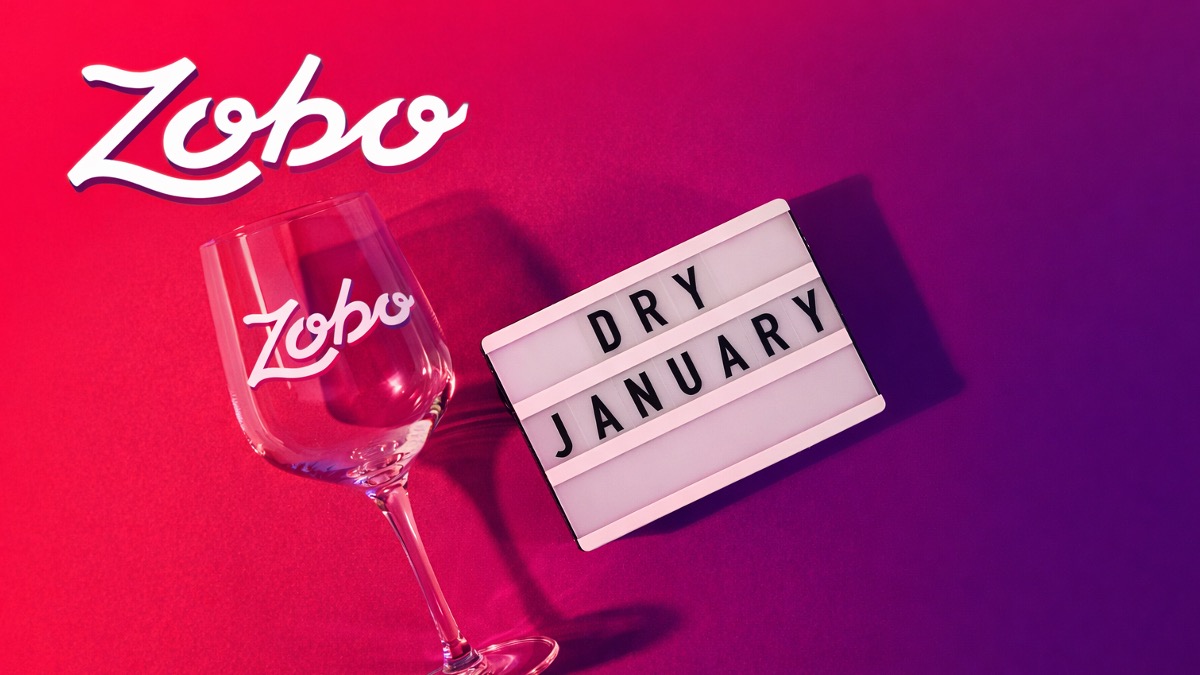 Empty Zobo branded wine glass beside a lightbox displaying 'DRY JANUARY' on a pink to purple gradient background.