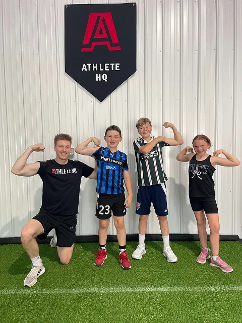 Group photo of youth athletes flexing with Coach Marty at Athlete HQ in Hamilton County, Indiana