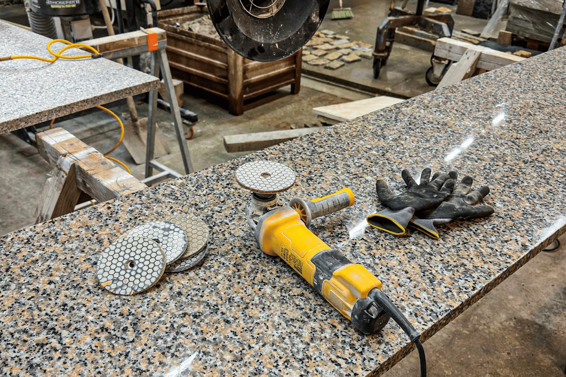 Ruční leštění hrany kamenné žulové desky v kamenické dílně.