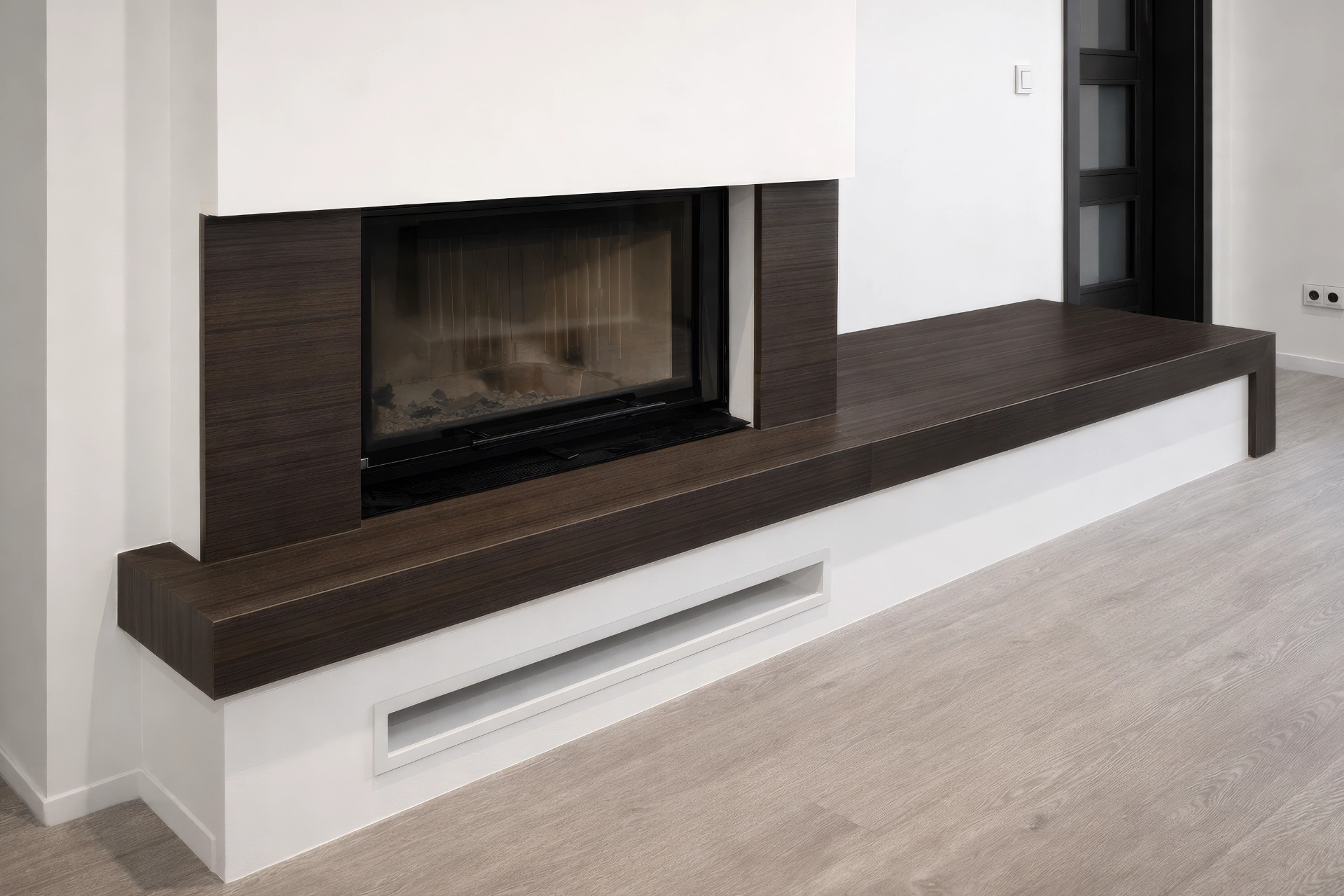 Široký moderní krb s tmavým dřevěným dekorem a integrovanou lavicí, zakázková realizace Kamenosochařství Hála.