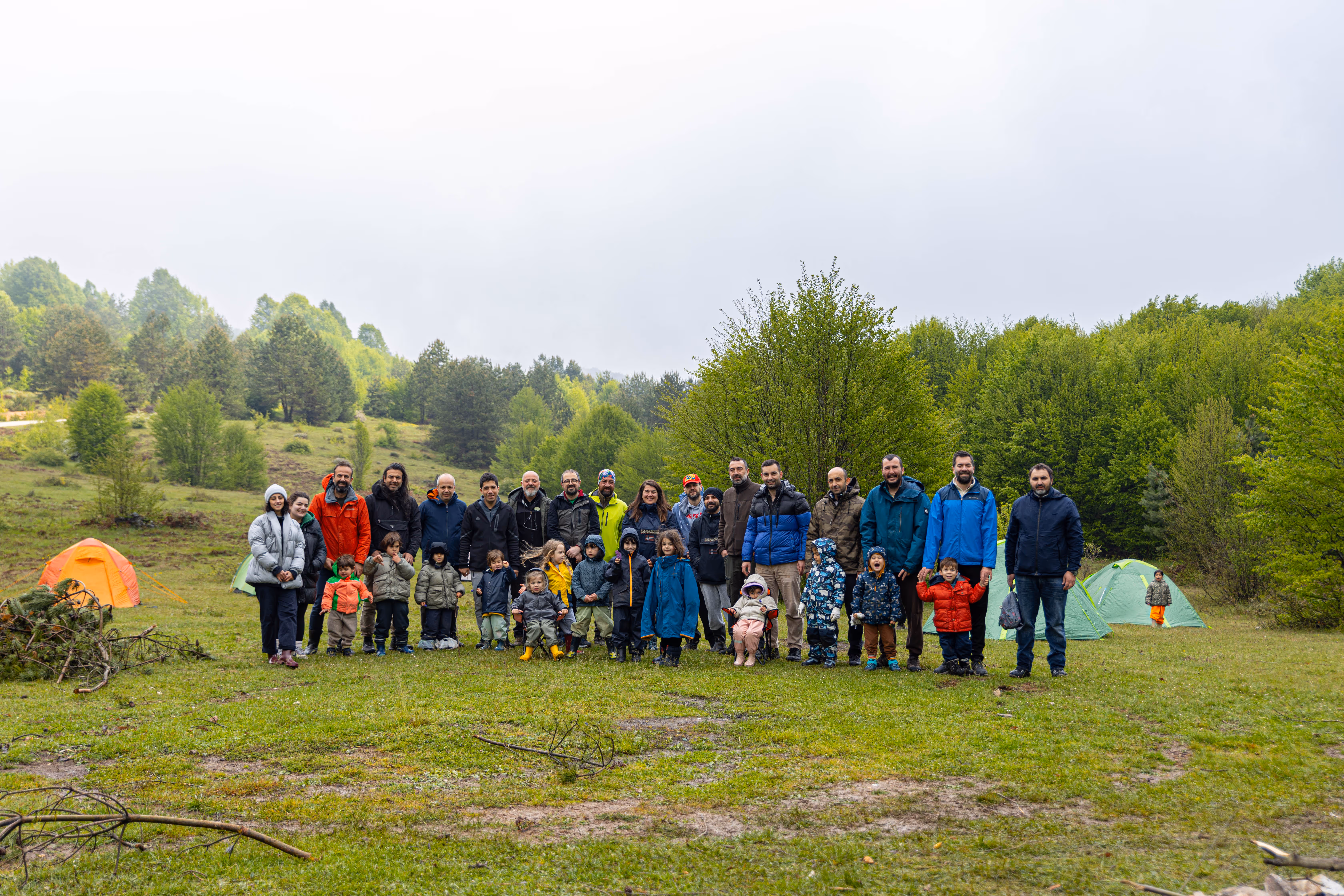 Ailelerin ve çocukların birlikte katıldığı doğa kampı etkinliğinde açık alanda toplu bir an.