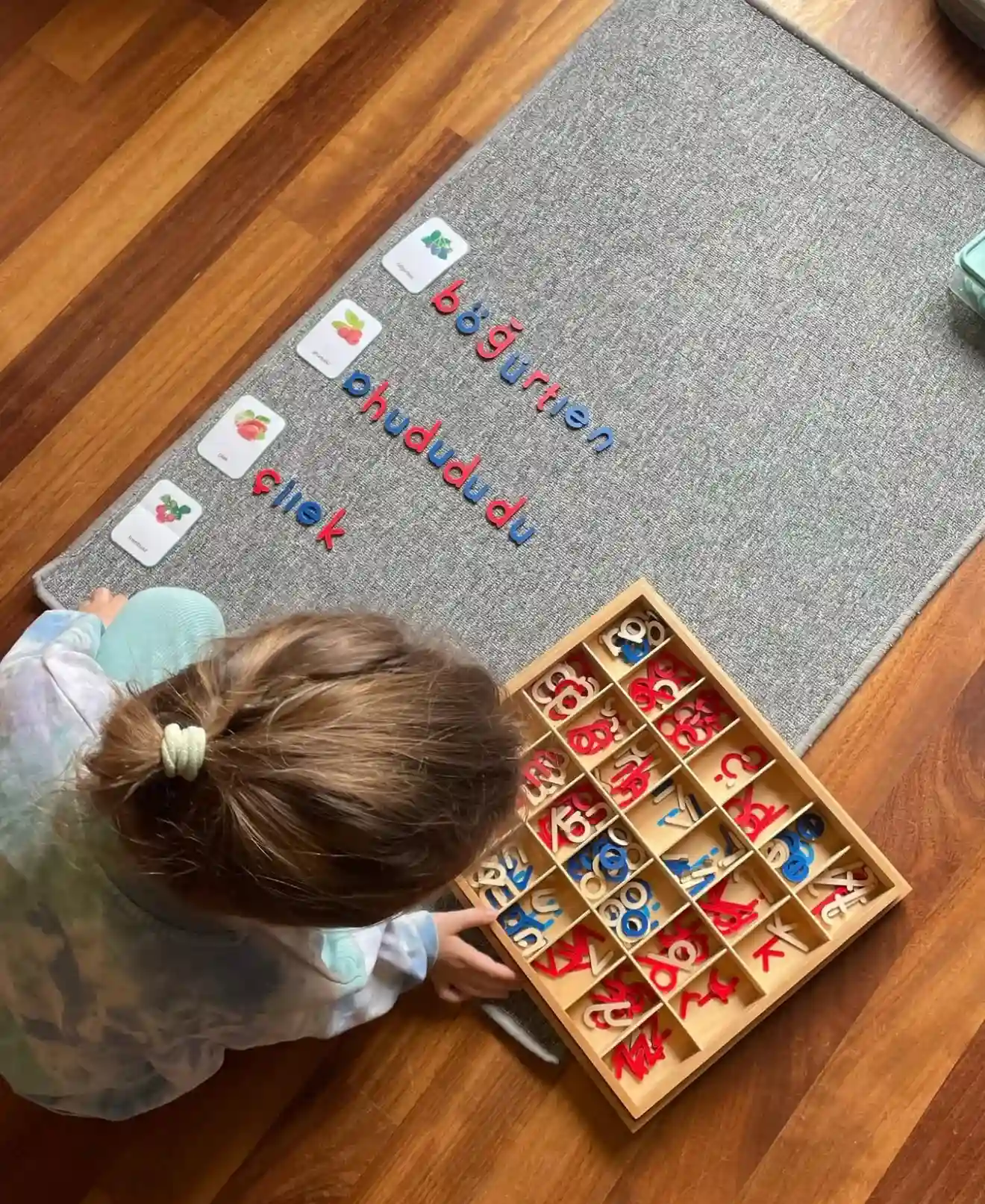 Montessori sınıfında harf kartları ve ahşap materyallerle yapılan erken okuma yazma çalışması.