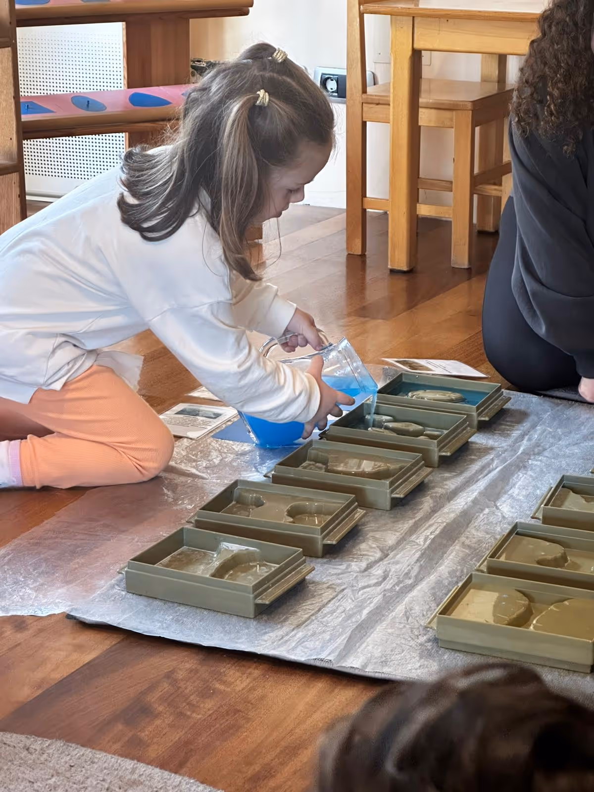 Montessori etkinliğinde bir çocuk, ölçü kabıyla su aktarımı yaparak ince motor becerilerini geliştiriyor.