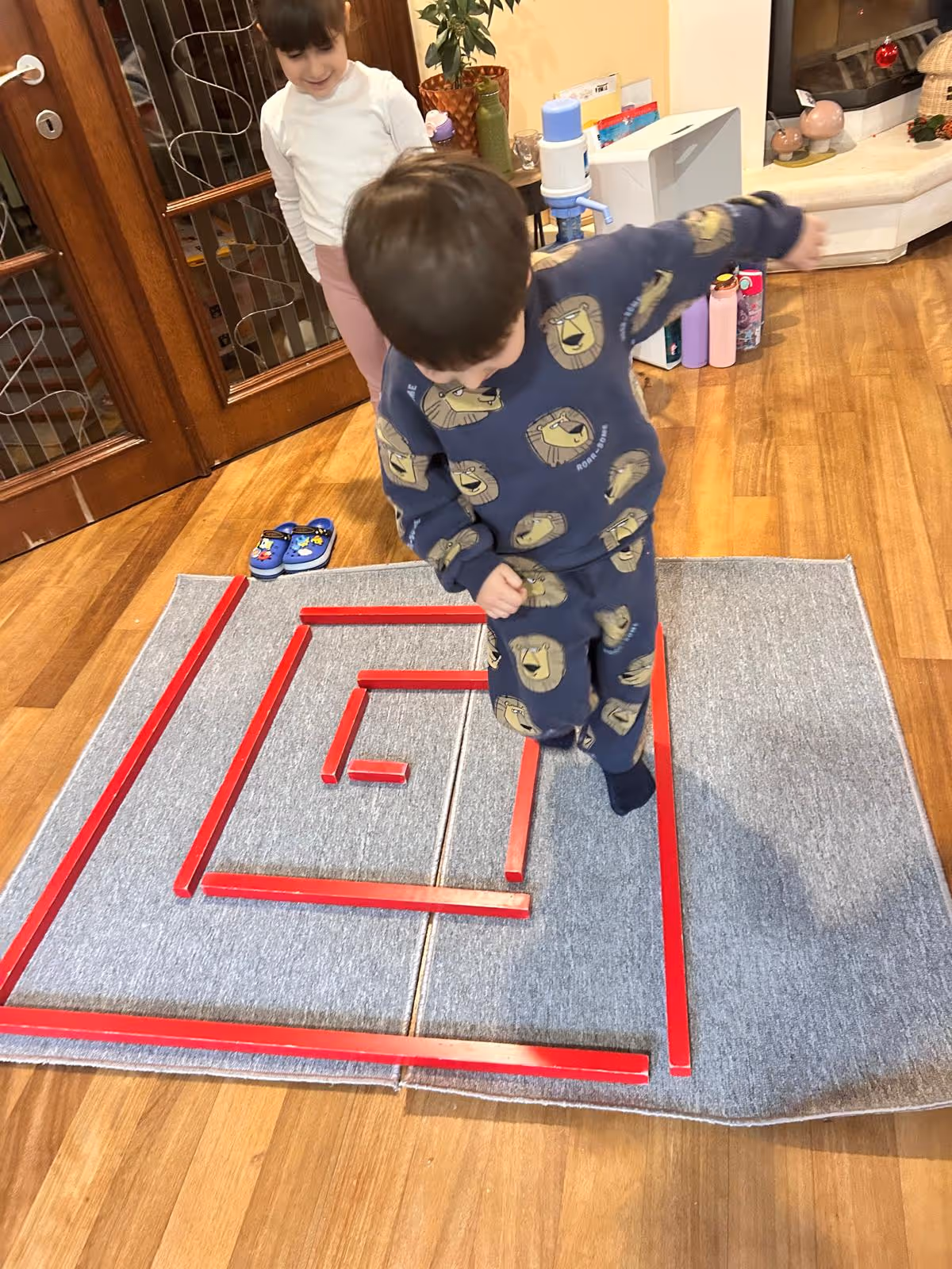 Montessori hareket etkinliğinde bir çocuk, yerdeki çizgiler üzerinde denge ve koordinasyon çalışması yapıyor.