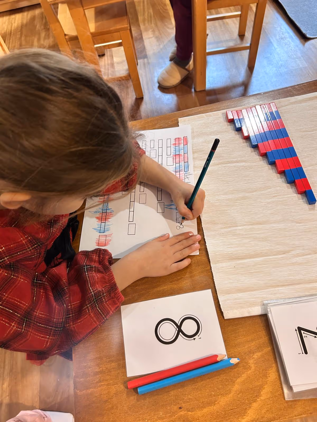 Montessori materyalleriyle yapılan sayı çizim ve eşleştirme çalışması sırasında çalışan bir çocuk.