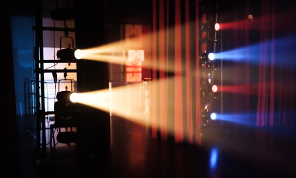 Spotlights on side booms with red and blue colour gels illuminating the backstage of Ngee Ann Polytechnic MusicBox's stage. Smoke/haze machine was used. The show was 2021 Chinese Dance's Arts Fiesta.