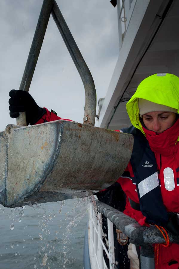 sole esnaola wearing weather proof clothes on a rainy day holding a an Veen grab being used to collect sediment samples from the seafloor