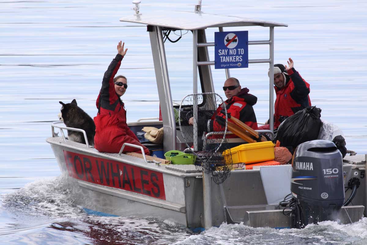 sole esnaola on a small research motor boat with two people an da dog waving to the camera out to look for whales