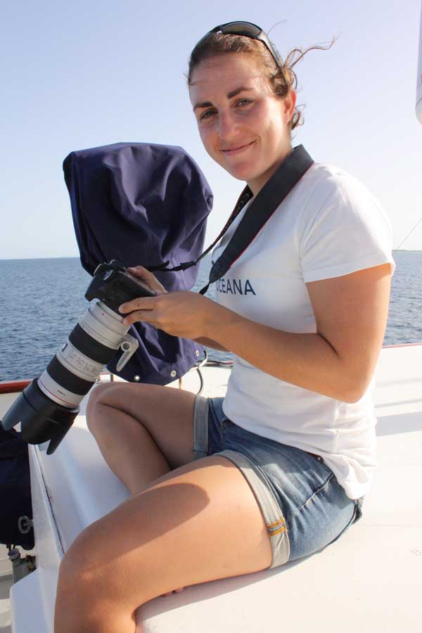 sole esnaola with a white Oceana t-shirt holding a photography camera with the ocean on the background