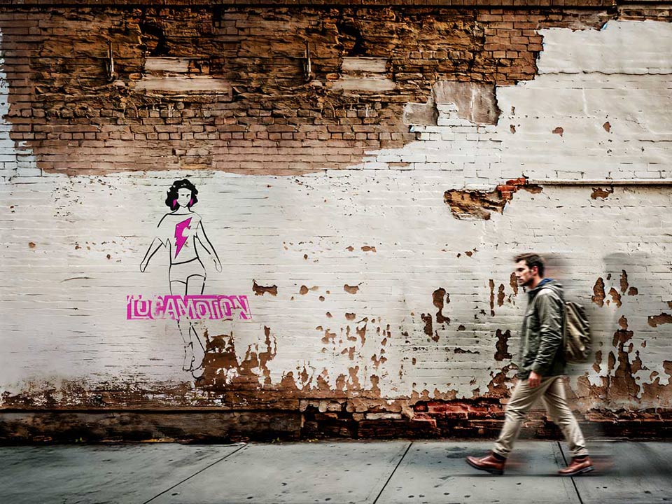 mockup of locamotion main logo print on a brick wall with a man walking on the right side
