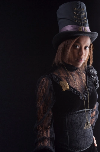 Girl in steampunk style outfit with a tall and laced top hat, black corset over a lace top.