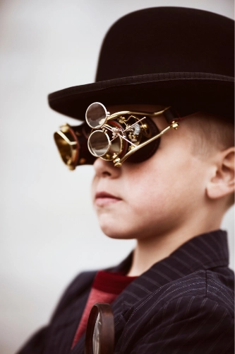 Boy dressed in steampunk style with bowler hat and onate goggles.