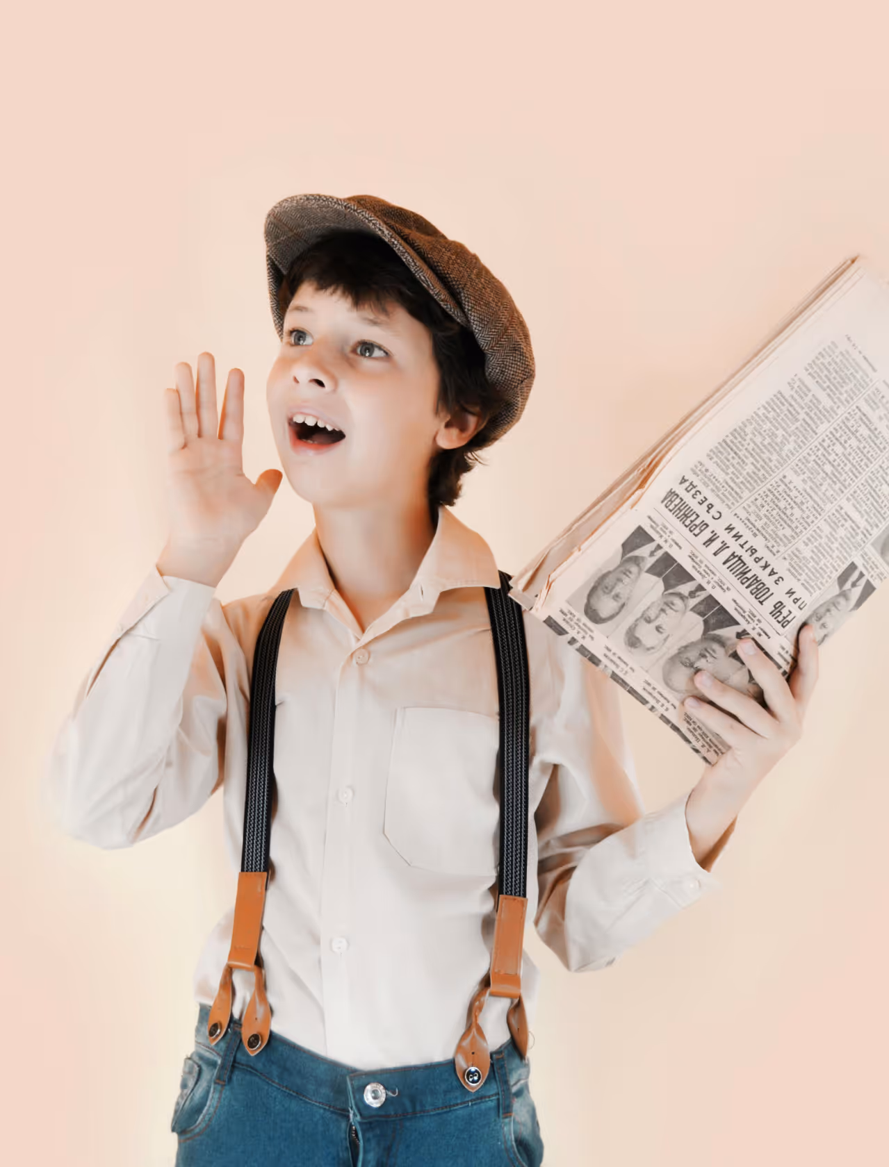 A boy wearing jeans, braces and a newsboy cap.
